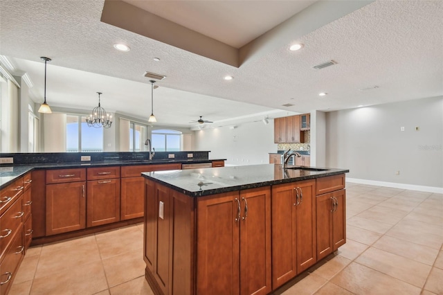 kitchen with pendant lighting, sink, a textured ceiling, and a center island with sink