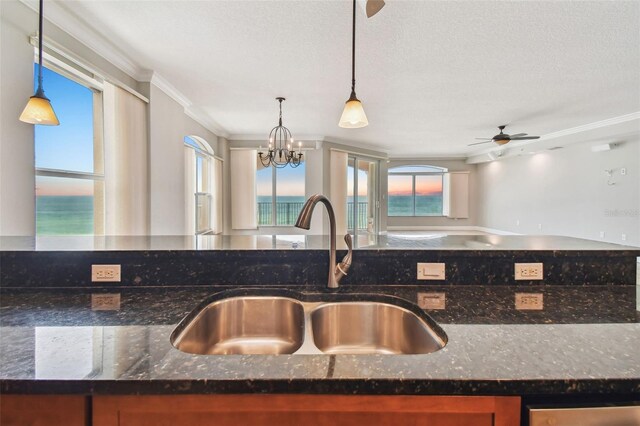 kitchen with hanging light fixtures, sink, and dark stone counters