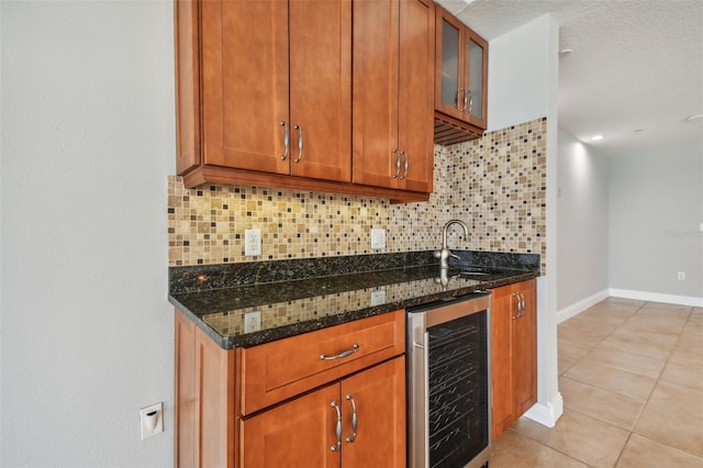 kitchen with sink, dark stone countertops, beverage cooler, and backsplash