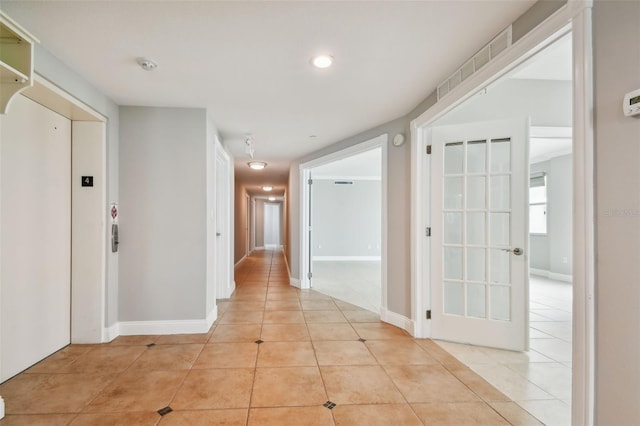 corridor with elevator and light tile patterned floors