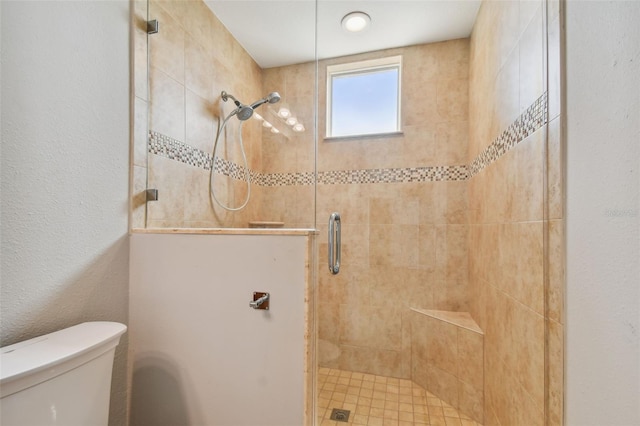 bathroom with a shower with shower door and toilet