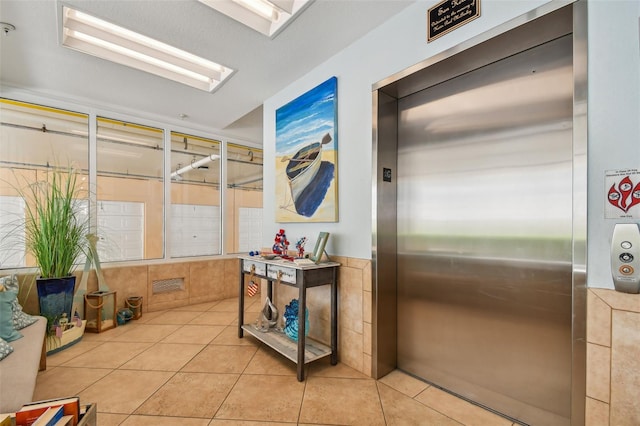 hall featuring light tile patterned floors, a wealth of natural light, and elevator