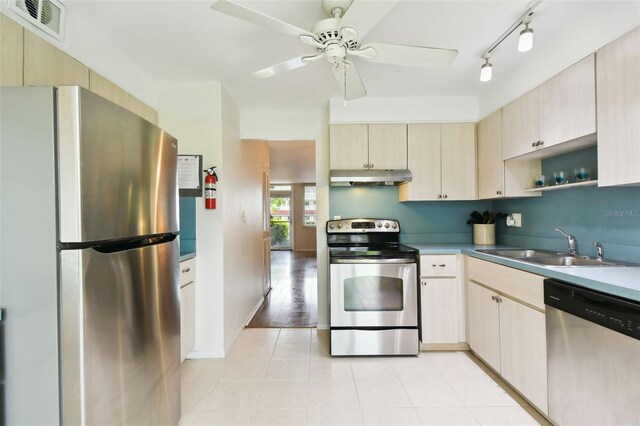 kitchen featuring rail lighting, light wood-type flooring, ceiling fan, appliances with stainless steel finishes, and sink