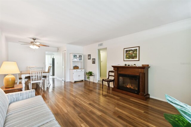 living room featuring ceiling fan and dark hardwood / wood-style flooring