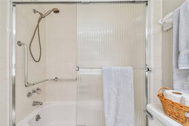 bathroom featuring bath / shower combo with glass door and toilet