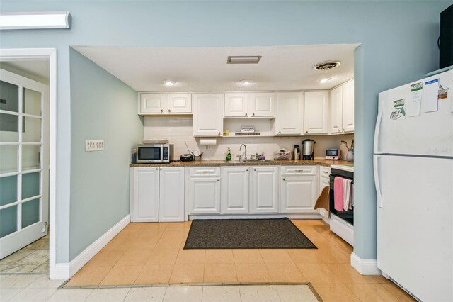 kitchen featuring sink, white cabinetry, white appliances, and light tile patterned floors