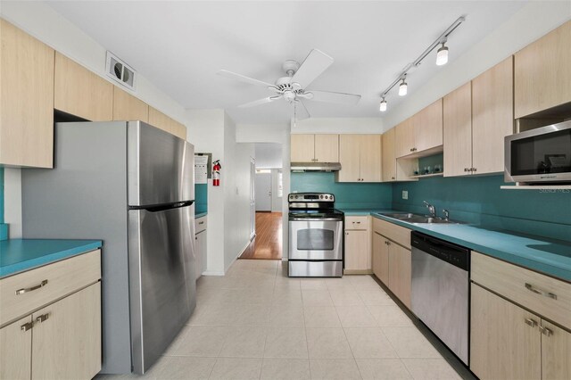 kitchen featuring appliances with stainless steel finishes, a sink, ceiling fan, and light brown cabinetry