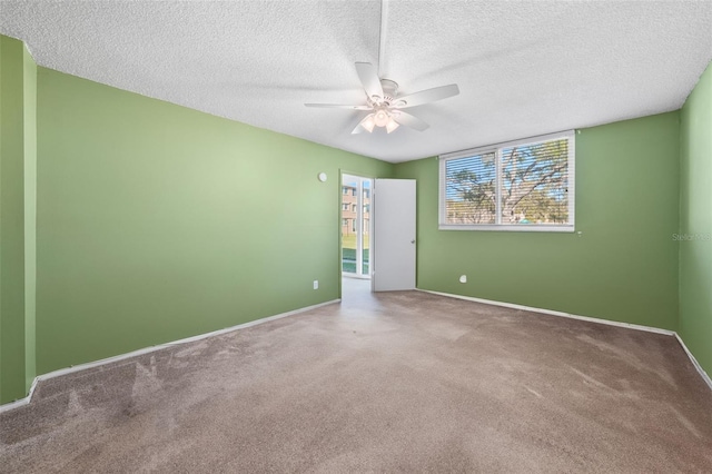 unfurnished room featuring a textured ceiling, carpet, a ceiling fan, and baseboards