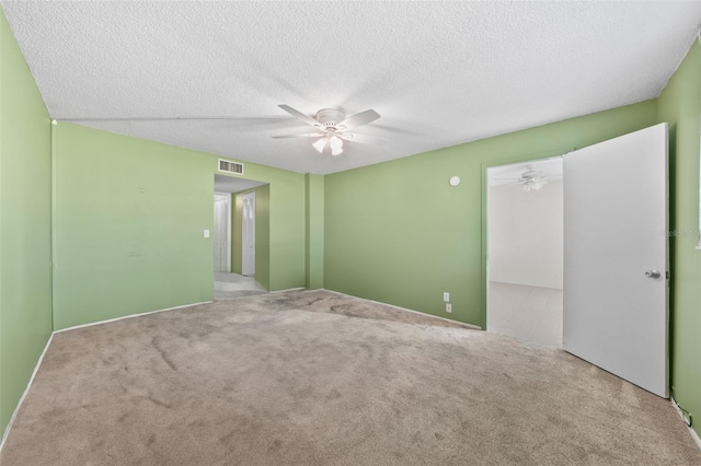 spare room featuring carpet, visible vents, ceiling fan, and a textured ceiling