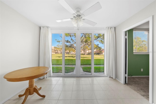 interior space featuring light tile patterned floors, baseboards, a ceiling fan, and light colored carpet