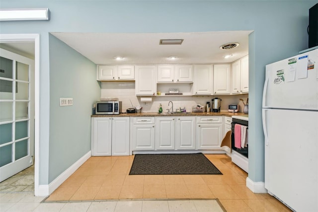 kitchen featuring a sink, visible vents, range, freestanding refrigerator, and stainless steel microwave