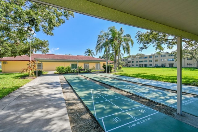 view of community featuring shuffleboard and a yard