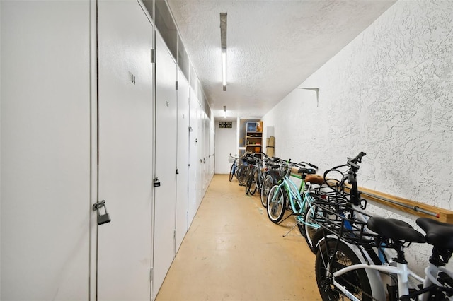 hallway featuring concrete floors, a textured wall, and a textured ceiling