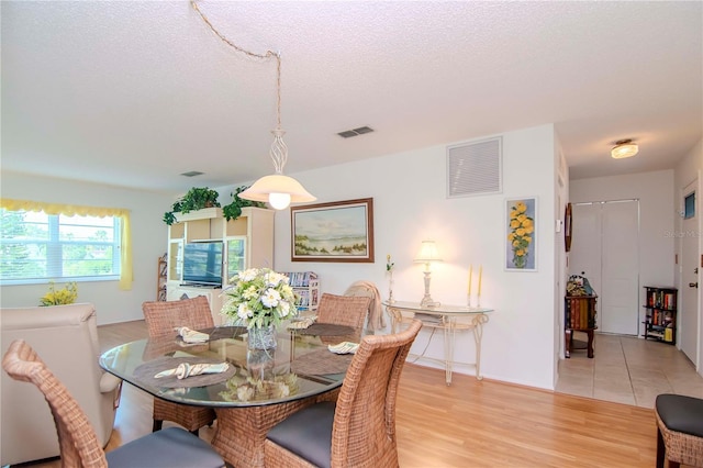 dining room with a textured ceiling and light hardwood / wood-style flooring