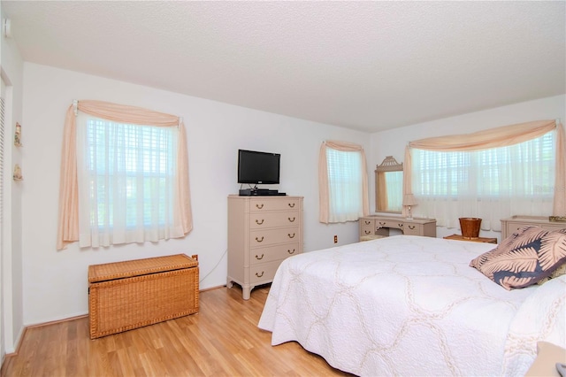 bedroom with light wood-type flooring and a textured ceiling