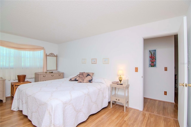 bedroom with a textured ceiling and light hardwood / wood-style flooring