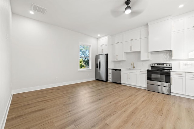 kitchen with ceiling fan, light hardwood / wood-style floors, white cabinets, sink, and stainless steel appliances