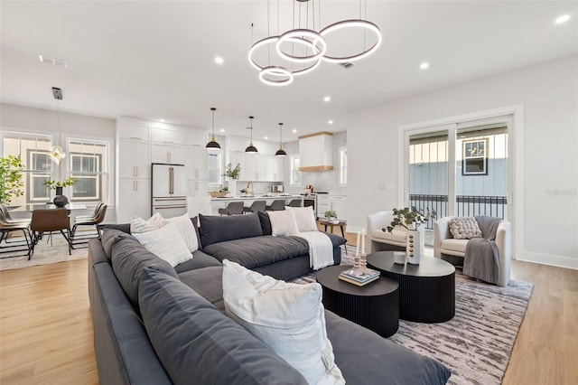 living room with an inviting chandelier and light hardwood / wood-style flooring