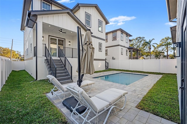 view of swimming pool with ceiling fan, a patio, and a lawn