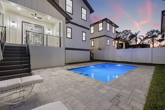 pool at dusk with a patio area and ceiling fan