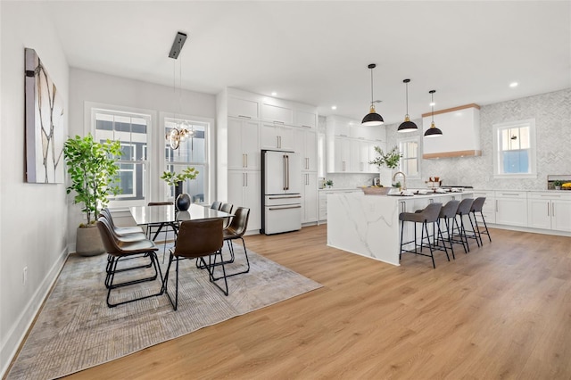 dining space with plenty of natural light, light hardwood / wood-style flooring, sink, and a notable chandelier