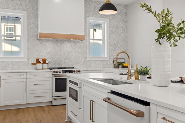 kitchen with white range with electric cooktop, white cabinetry, stainless steel dishwasher, sink, and decorative light fixtures