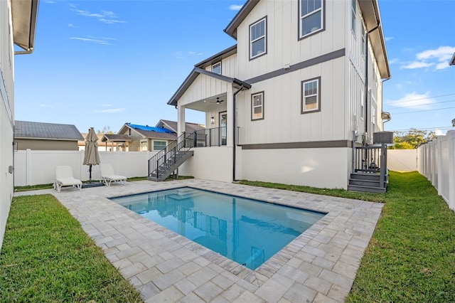 rear view of property with a fenced in pool, a patio area, ceiling fan, and a lawn