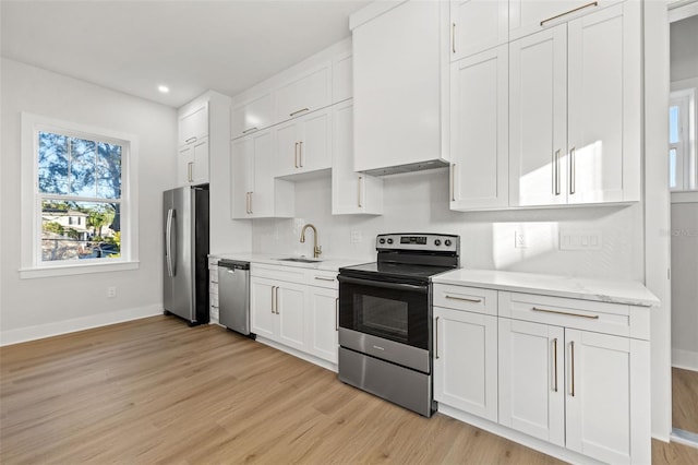 kitchen featuring white cabinetry, sink, light hardwood / wood-style flooring, stainless steel appliances, and light stone counters