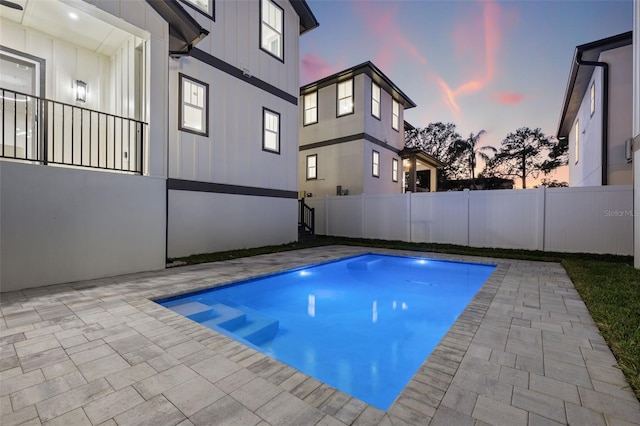 pool at dusk featuring a patio area