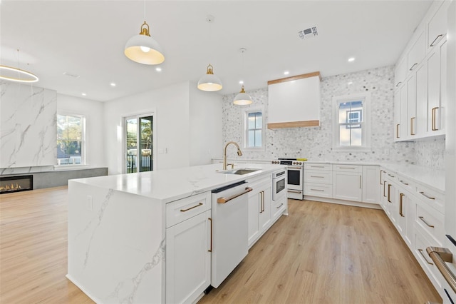 kitchen featuring premium range hood, white appliances, a kitchen island with sink, white cabinets, and hanging light fixtures