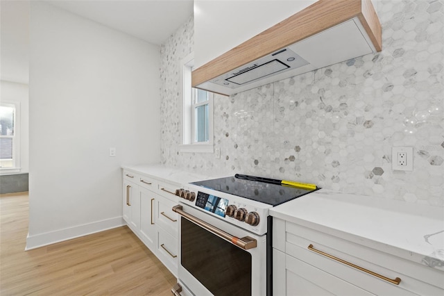 kitchen with white cabinetry, stainless steel range, plenty of natural light, and ventilation hood