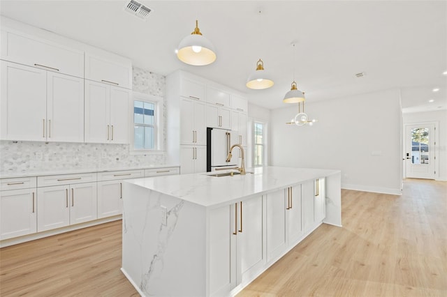 kitchen featuring sink, pendant lighting, a center island with sink, white cabinets, and plenty of natural light