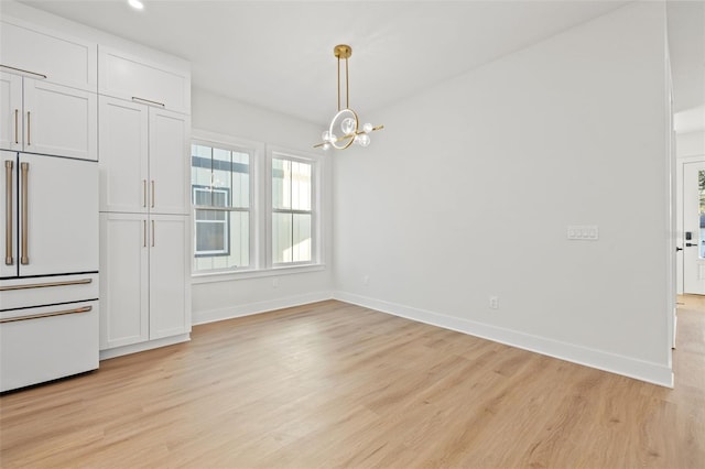 unfurnished dining area featuring light hardwood / wood-style flooring and an inviting chandelier