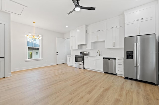 kitchen featuring white cabinets, sink, appliances with stainless steel finishes, decorative light fixtures, and light hardwood / wood-style floors