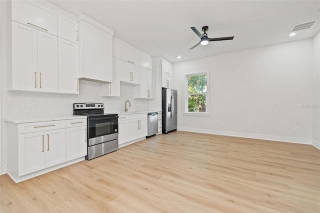 kitchen with stainless steel appliances, white cabinetry, light hardwood / wood-style floors, and sink