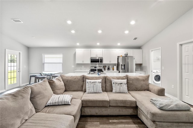 living room featuring sink, washer / clothes dryer, dark hardwood / wood-style flooring, and vaulted ceiling