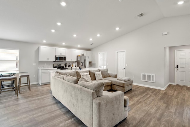 living room featuring high vaulted ceiling and light wood-type flooring