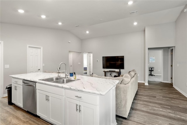 kitchen featuring sink, dishwasher, white cabinetry, light stone countertops, and an island with sink