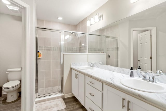 bathroom featuring hardwood / wood-style flooring, vanity, toilet, and a shower with door