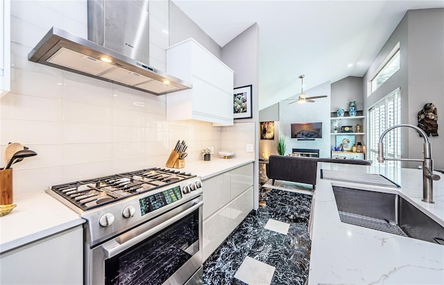 kitchen with lofted ceiling, high end stainless steel range, wall chimney exhaust hood, decorative backsplash, and white cabinetry