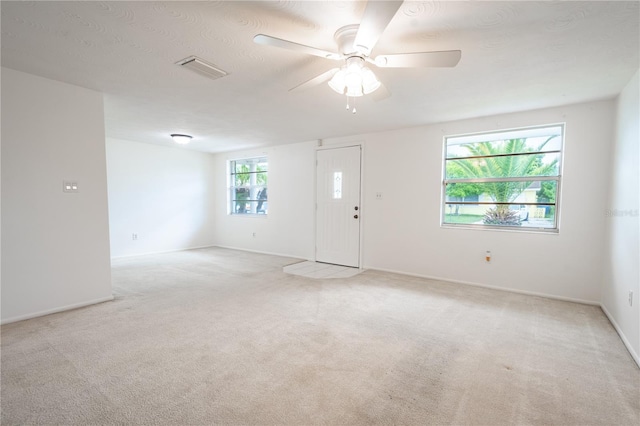 unfurnished room featuring light carpet, plenty of natural light, and ceiling fan