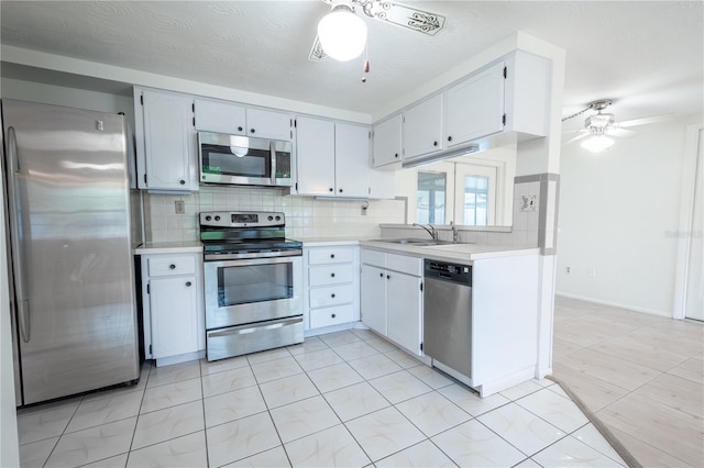 kitchen with backsplash, sink, ceiling fan, appliances with stainless steel finishes, and white cabinetry