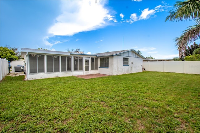 rear view of property featuring a sunroom, central AC unit, and a yard