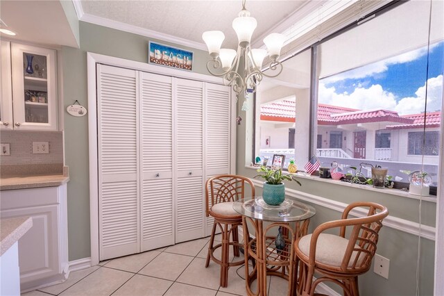 dining space featuring crown molding, an inviting chandelier, and light tile patterned floors