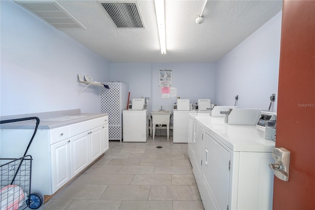 washroom with cabinet space, visible vents, separate washer and dryer, and a textured ceiling