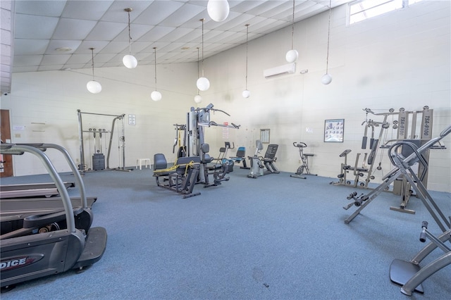 gym featuring an AC wall unit and a towering ceiling