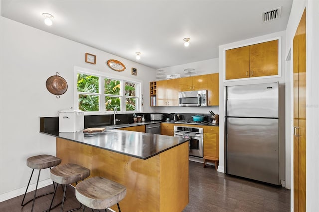 kitchen with appliances with stainless steel finishes, a breakfast bar, sink, and kitchen peninsula