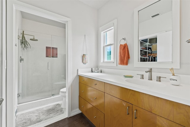 bathroom with hardwood / wood-style flooring, vanity, toilet, and a shower with door