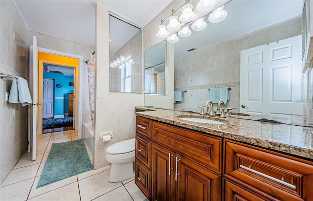 bathroom featuring toilet, vanity, tile walls, and tile patterned floors