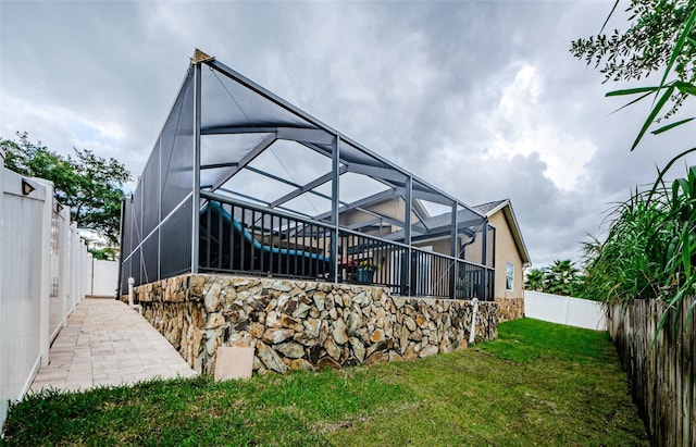 back of house featuring glass enclosure and a lawn